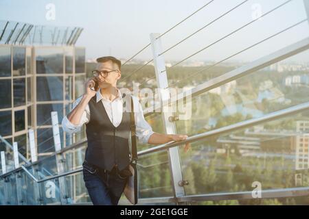 young businessman with a smartphone standing on the stairs in th Stock Photo