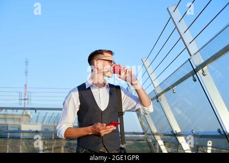 businessman with a smartphone drinks coffee on the office terrace . Stock Photo