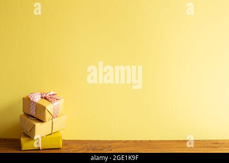 Stack of yellow gift boxes on wooden table. yellow wall background Stock Photo