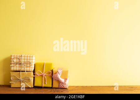 Yellow gift boxes on wooden table. yellow wall background Stock Photo