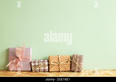 Colorful gift boxes on wooden table. green wall background Stock Photo