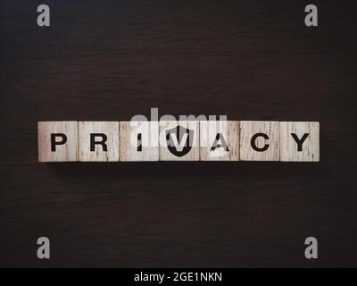 Privacy concept. Word 'PRIVACY' on wooden blocks with a shield icon on dark wooden background, top view. Personal data protection and non-infringement Stock Photo