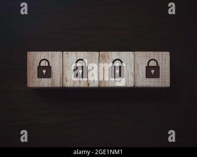 Privacy and personal data protection concept. Four lock icon on wooden blocks on dark wooden background, top view. Password security. Stock Photo