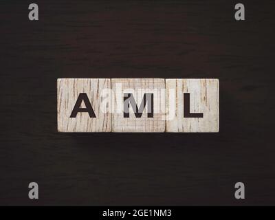 Anti Money Laundering Concept. Word "AML" on wooden blocks with on dark wooden background, top view. Personal data protection and non-infringement of Stock Photo