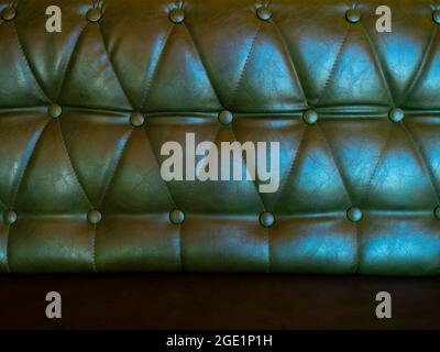 Leather sofa with pins and buttons background. Close up of vintage dark green long leather sofa seat texture background. Stock Photo