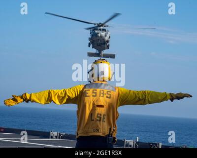 210811-N-WY048-3282    PACIFIC OCEAN (Aug. 11, 2021) – Aviation Boatswain’s Mate Airman Ethan Bowser directs an MH-60S Sea Hawk from Helicopter Sea Combat Squadron (HSC) 23 aboard expeditionary sea base USS Miguel Keith (ESB 5), Aug. 11. HSC 23 is embarked aboard Miguel Keith conducting routine operations in U.S. 3rd Fleet. (U.S. Navy photo by Mass Communication Specialist 2nd Class Hector Carrera) Stock Photo