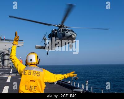 210811-N-WY048-3269    PACIFIC OCEAN (Aug. 11, 2021) – Aviation Boatswain’s Mate Airman Ethan Bowser directs an MH-60S Sea Hawk from Helicopter Sea Combat Squadron (HSC) 23 aboard expeditionary sea base USS Miguel Keith (ESB 5), Aug. 11. HSC 23 is embarked aboard Miguel Keith conducting routine operations in U.S. 3rd Fleet. (U.S. Navy photo by Mass Communication Specialist 2nd Class Hector Carrera) Stock Photo