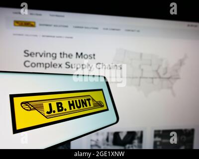 Mobile phone with logo of logistics company J.B. Hunt Transport Services Inc. on screen in front of website. Focus on center-left of phone display. Stock Photo