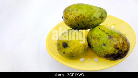 Three large ripe mangoes in a basket isolated on white background Stock Photo
