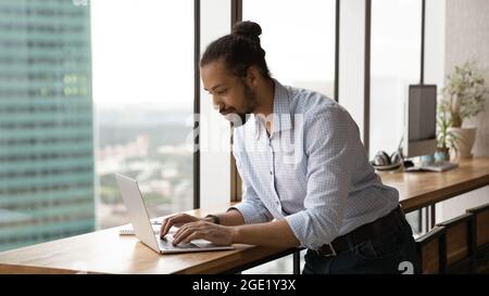 African businessman working on laptop standing in modern office Stock Photo