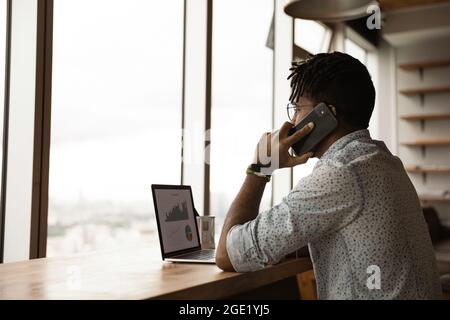 African entrepreneur talking on phone discuss with colleague sales statistics Stock Photo