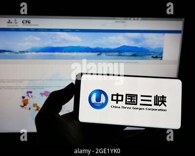 Person holding cellphone with logo of power company China Three Gorges Corporation (CTG) on screen in front of webpage. Focus on phone display. Stock Photo