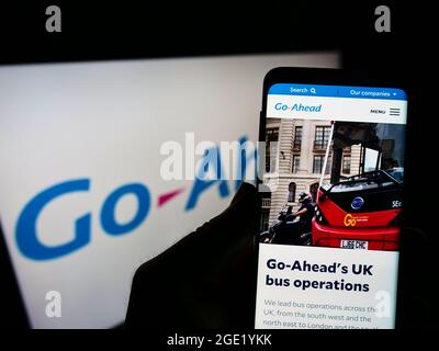 Person holding cellphone with webpage of British transport company The Go-Ahead Group plc on screen with of logo. Focus on center of phone display. Stock Photo