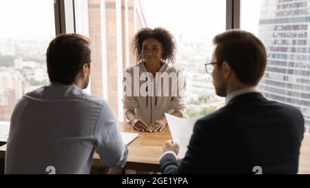 Rear back view HR male managers interviewing African female applicant Stock Photo