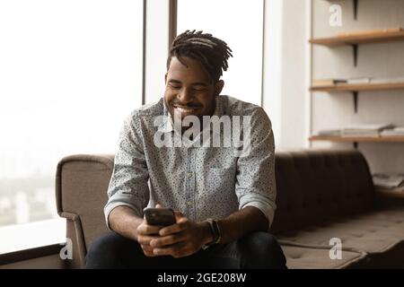 African man smiling look at smartphone chatting online Stock Photo