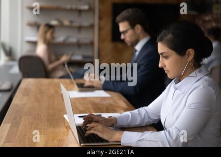 Indian woman working on computer sit in coworking space Stock Photo
