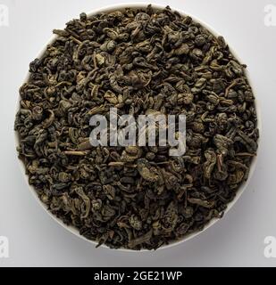 Dried Chinese Gunpowder green tea leaves in a bowl, on a white background Stock Photo
