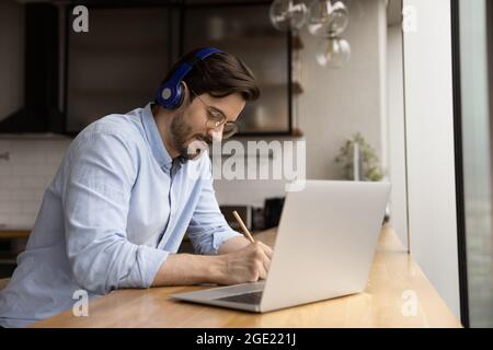 Man wear headphones listens audio course studying at home Stock Photo