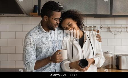 African loving couple standing in modern kitchen holding coffee cups Stock Photo