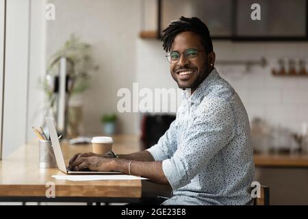 Portrait of smiling African freelancer guy working on laptop Stock Photo