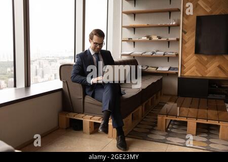 Businessman in formal suit sit in office texting on laptop Stock Photo