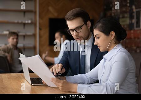 Indian and Caucasian businesspeople work together in coworking space Stock Photo