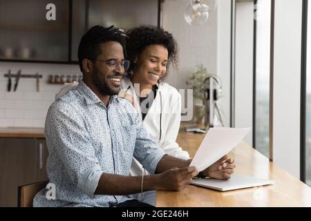 African couple holding papers reading document glad about good news Stock Photo