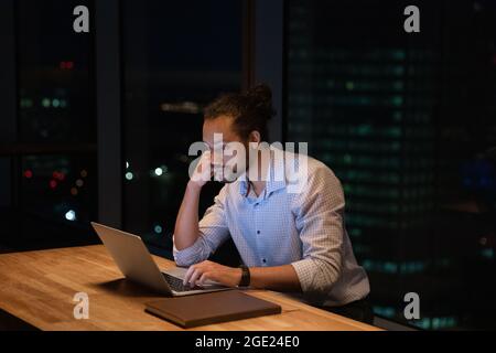 African businessman stay late in modern office working using computer Stock Photo