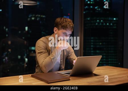 Young employee working on laptop until late in office Stock Photo