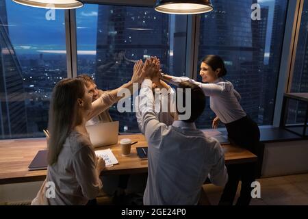 Multi ethnic employees accomplish meeting giving high five feels overjoyed Stock Photo
