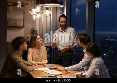 Group of diverse employees working in office boardroom until late Stock Photo