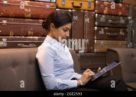 Serious Indian businesswoman sit in modern office hall with tablet Stock Photo