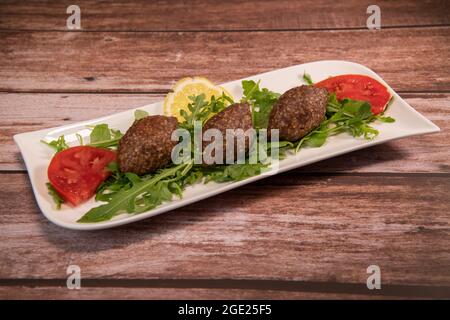 Traditional kebbe and pita bread on big round plate in lebanese restaurant Stock Photo