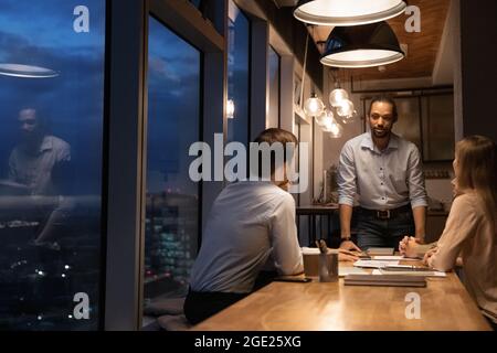 Group of diverse colleagues working until late in modern office Stock Photo