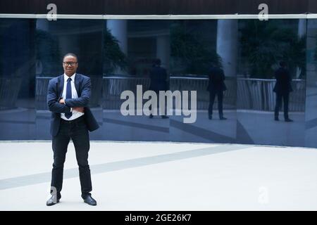 Full-length portrait of positive confident entrepreneur standing outdoors, crossing arms and looking at camera Stock Photo