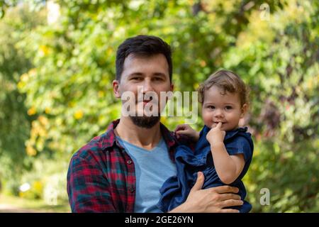 A young father holds his little daughter in his arms, a happy family. Caucasian man and little baby girl 1 year old Stock Photo