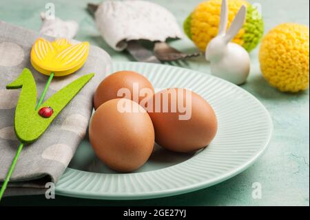 Easter composition with plate, eggs, decorative rabbit on blue cocnrete background Stock Photo