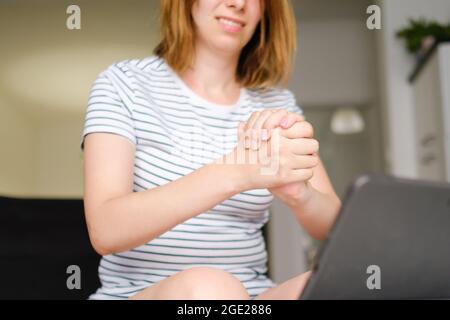 Smiling young woman using laptop for online talking with colleges or friends. Freelancer working at home. Stock Photo