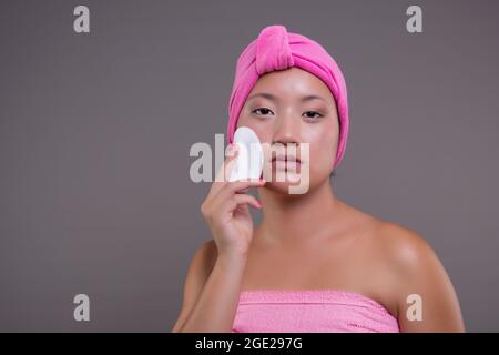 Young Chinese girl taking care of her skin after showering, beauty concept Stock Photo