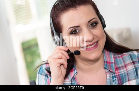 Young beautiful woman with headset working from home Stock Photo