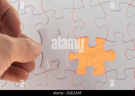 A hand hold the missing piece of white jigsaw puzzle Stock Photo