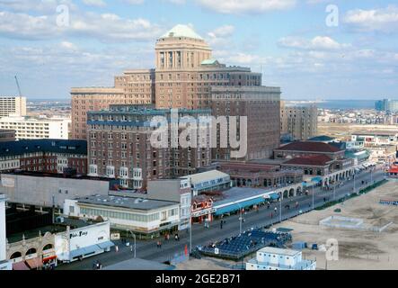 Atlantic City with the ‘Chalfonte-Haddon Hall’ hotel complex behind the famous boardwalk and the beach in the 1960s. The resort city in New Jersey, USA is known for its hotels and casinos. The first boardwalk was built in 1870 to help keep sand out of the hotels. The Chalfonte House (Chalfonte Hotel), opened in 1904, is an eight-storey brick building. The larger Haddon Hall was built during the 1920s. Today it is ‘Resorts’ Casino Hotel. It added a 27-storey Rendezvous Tower in 2004 – the two earlier buildings were painted white – this image is from a 60s American amateur colour transparency. Stock Photo