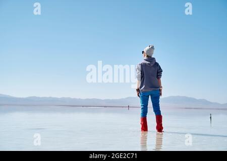 asian woman standing in the water of a salt lake looking at view Stock Photo