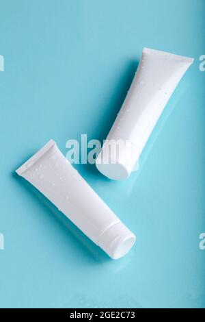 Mock up skincare cosmetic package on blue. Water balance cosmetic product. White cosmetic product in tubes on color background with water drops Stock Photo