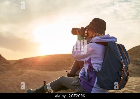 asian woman female photographer taking a photo of landscape in gobi desert with yardang landforms at sunset Stock Photo