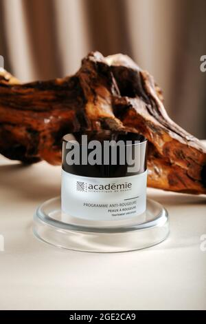 Academie Cream for skin on wooden bark beige background with laboratory glassware. Face cream on pedestal. Editorial product photography. Skin care Stock Photo