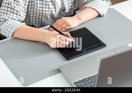Creative designer working with professional equipment. Close up female hands designer editor artist drawing digital tablet laptop at home office Stock Photo