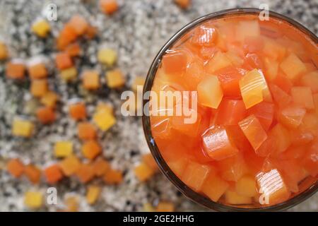red and yellow tropical fruit papaya tree cut into square dice in the food and drink album, summer relaxation, in the garden corner on the stone table Stock Photo