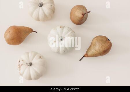 Autumn fruit and vegetable composition. Food pattern made of white pumpkins and fresh pear isolated on beige table background. Fall, Halloween and Stock Photo
