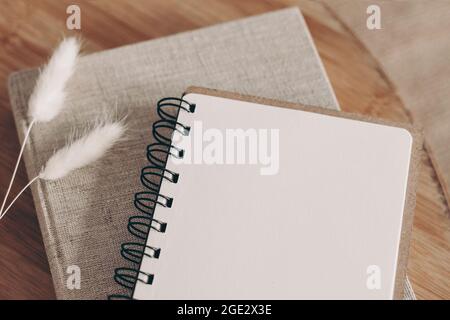 Closeup of empty diary, notepad mockup and book on wooden table. Dry Lagurus ovatus grass, blurred background. Top view. Decorative autumn office Stock Photo